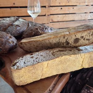 Domač kruh iz droži, pečen v krušni peči, postrežen na leseni mizi.